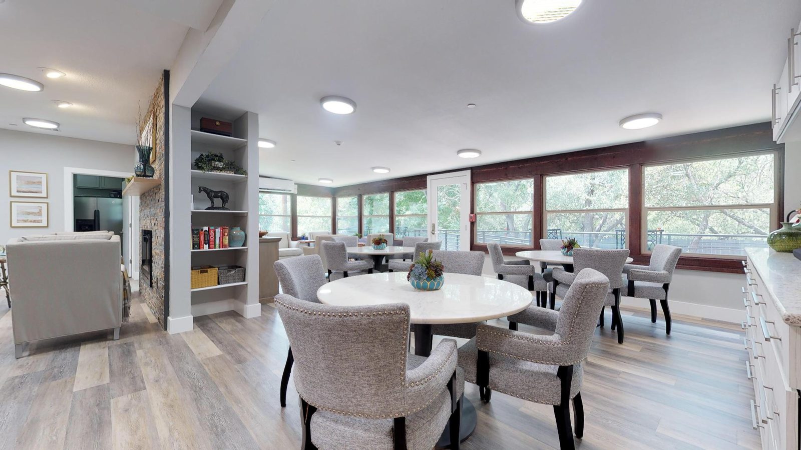 Dining room with marble tables, upholstered chairs and a wall of windows