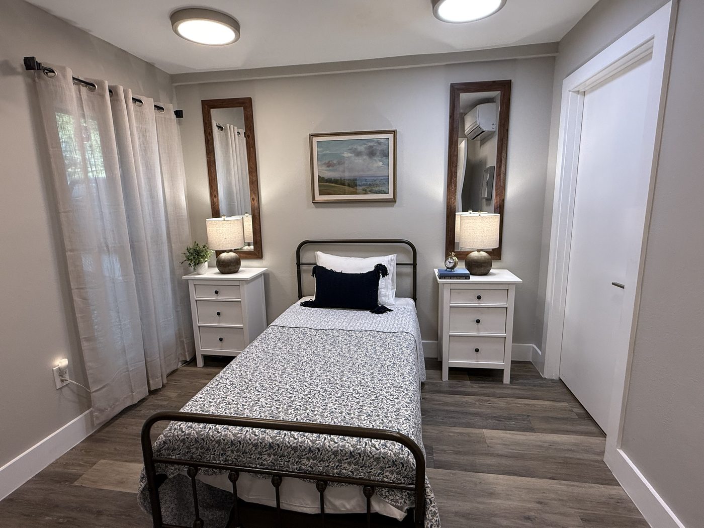 Resident room with iron bed, matching nightstands, lamps and tall mirrors